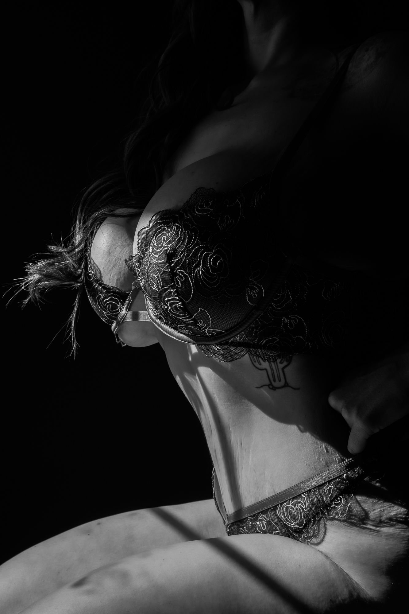 Black and white artistic photograph showing a woman's shoulder and neck with delicate lace details.