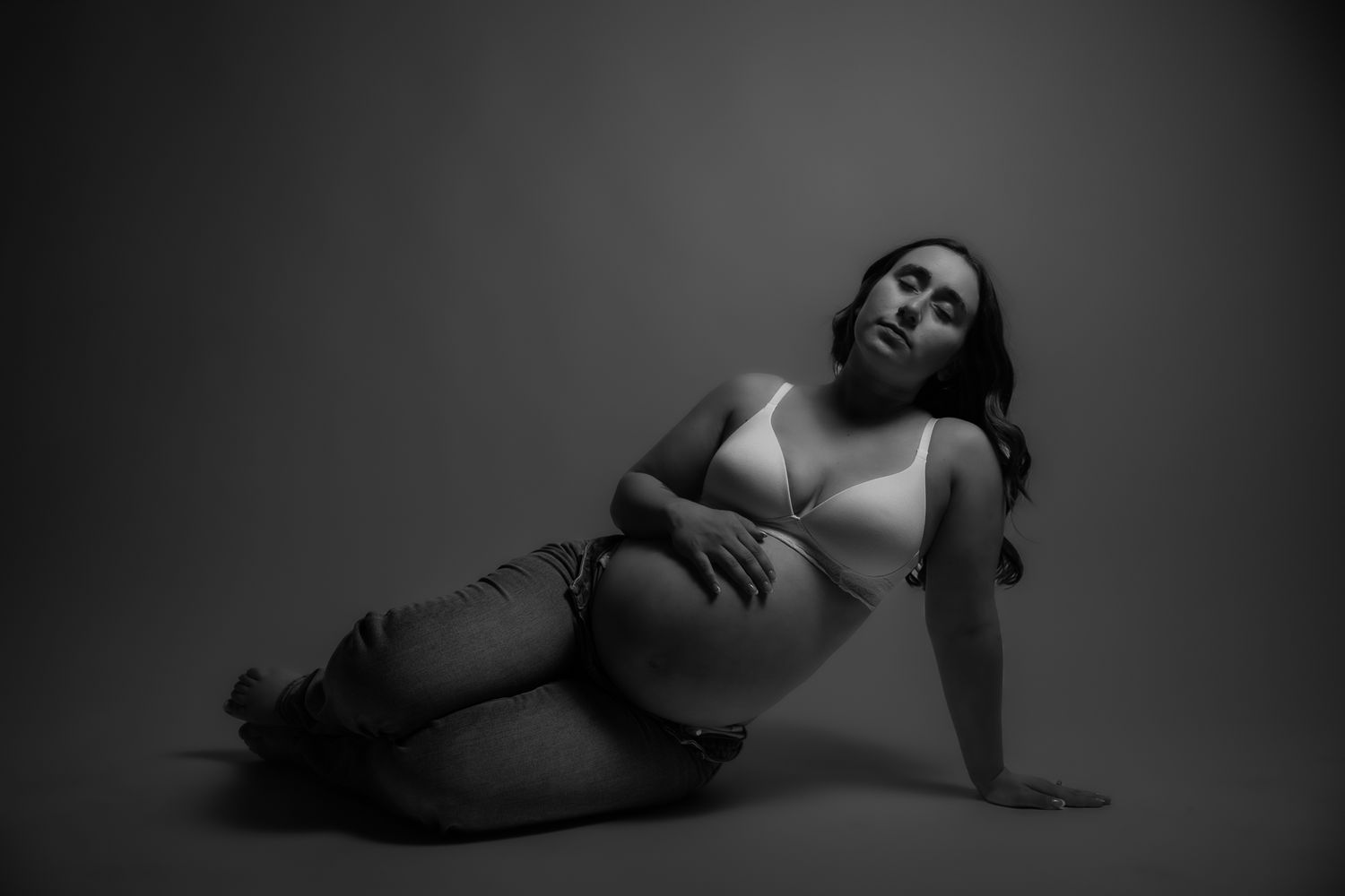 Black and white artistic boudoir photography series showing dramatic poses in low light against dark background. Arizona studio