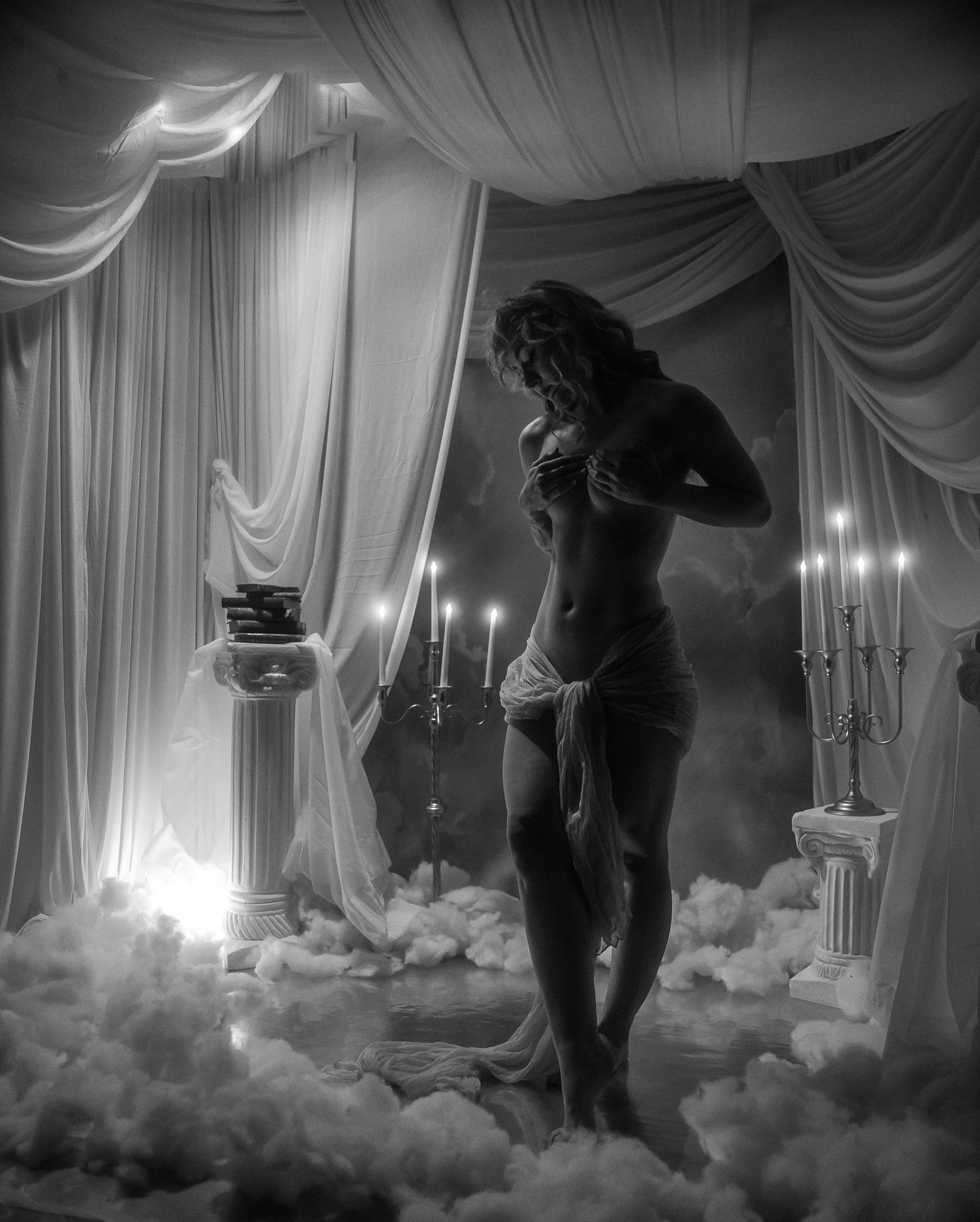 Atmospheric black and white film sequence showing a silhouette walking through a misty, curtained room with candlelight.