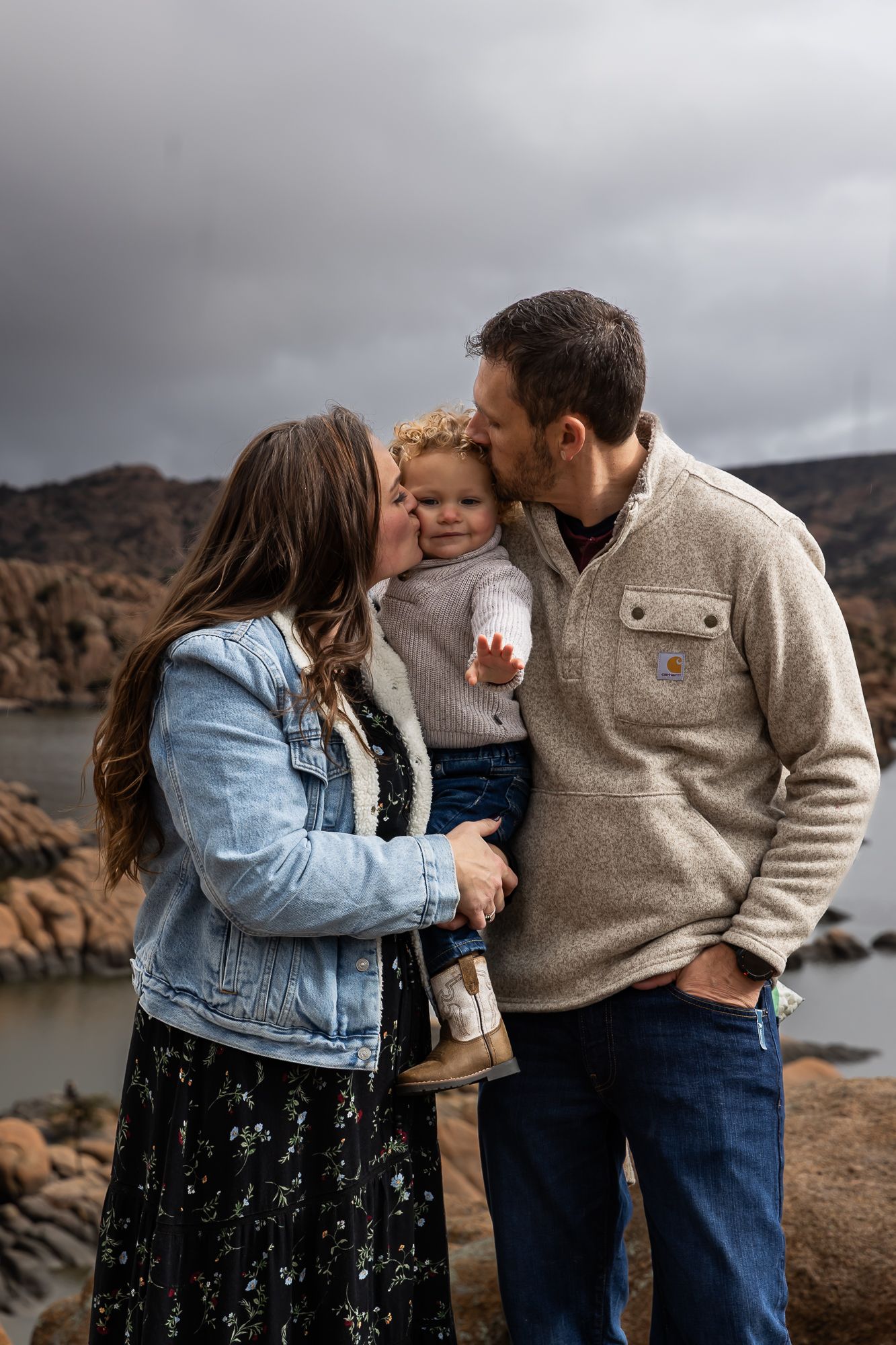A couple shares intimate moments on a rocky coastline with dramatic cloudy skies in the background. arizona Prescott Watson lake