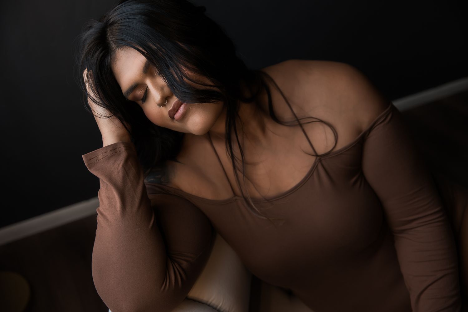 A dark and moody portrait photo of someone with long dark hair against a black background.