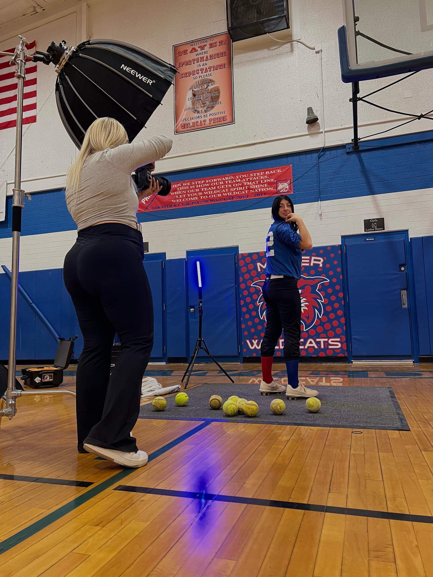 An arizonaphoto shoot setup in a school gymnasium with lighting equipment and people working on capturing athletic content.