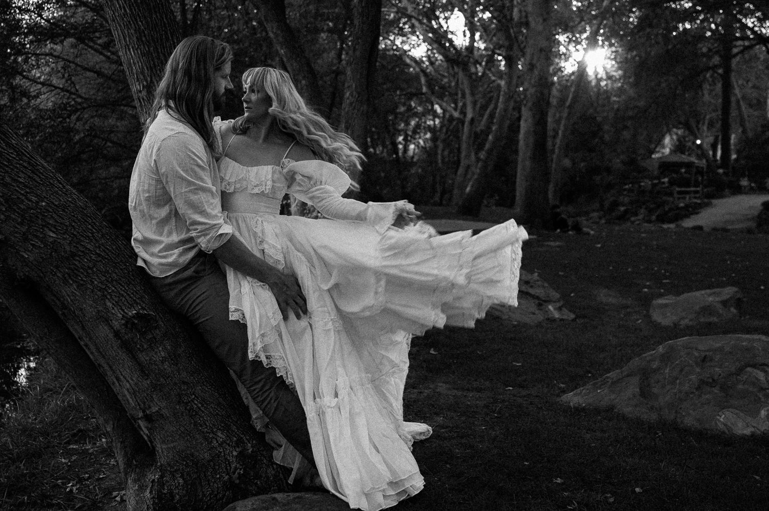 A person in a flowing white dress twirls gracefully in a dark wooded setting during a photoshoot. Cosplay, Arizona , tlaquepaque