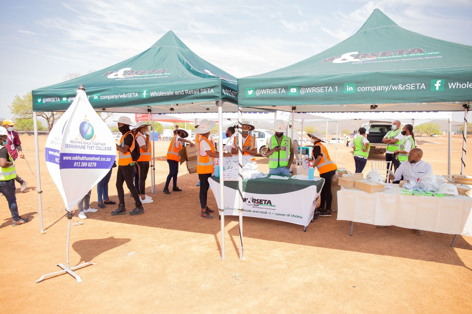 Visitors browse green SETA information tents at an outdoor infrastructure skills development event.