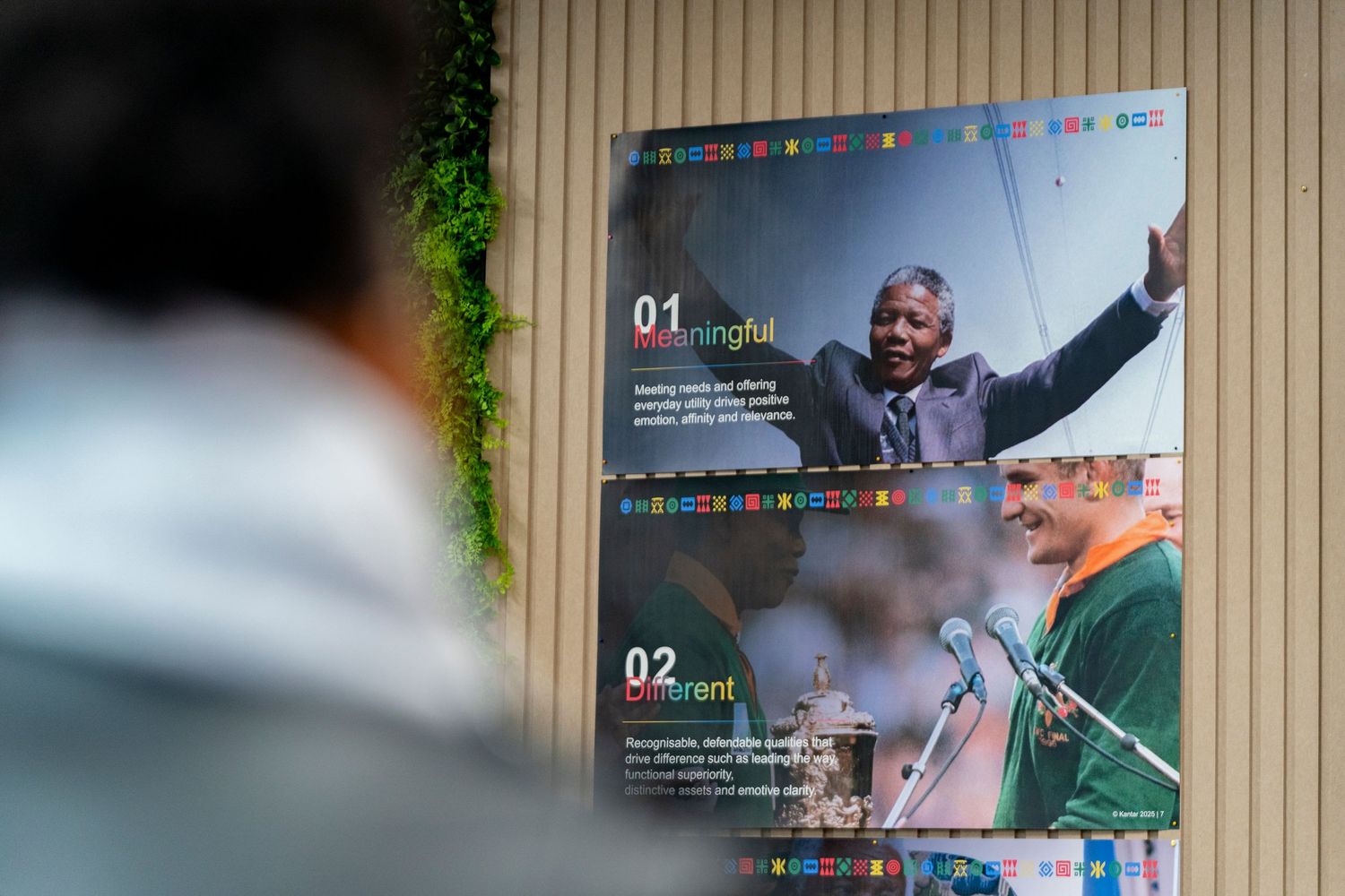 Person viewing a display board featuring Nelson Mandela photos with numbered leadership principles in an exhibit.