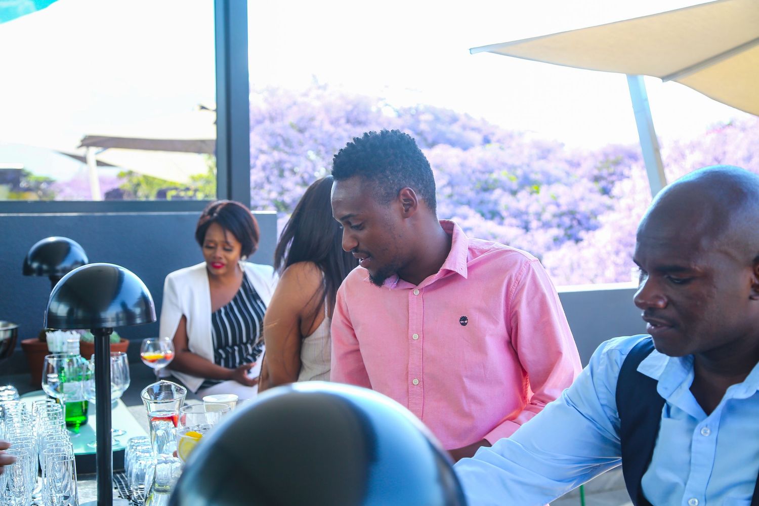Guests socialize and dine together at an indoor event with large windows and lush views.