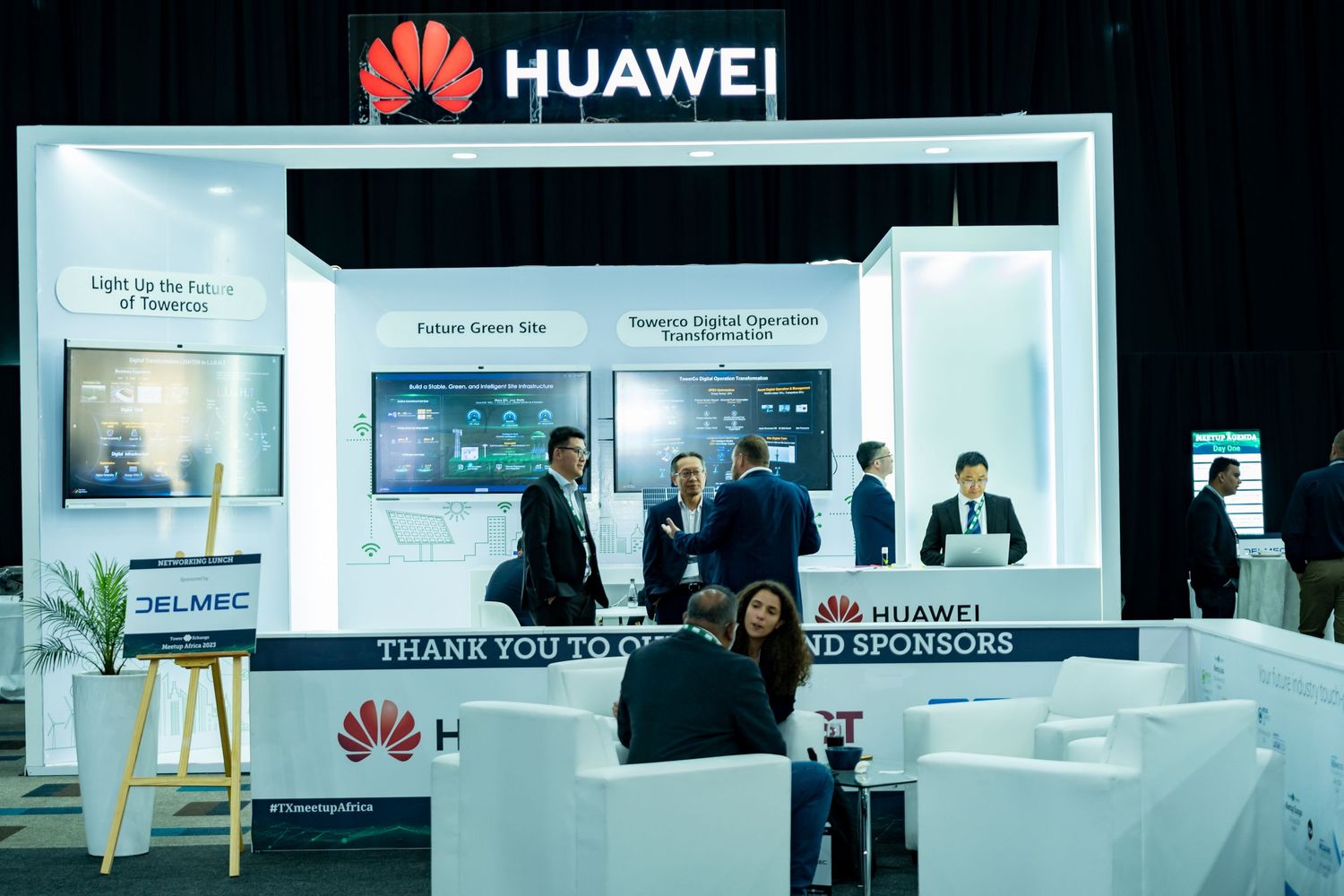 Huawei exhibition booth at TowerXchange Meetup Africa with attendees networking near display screens.