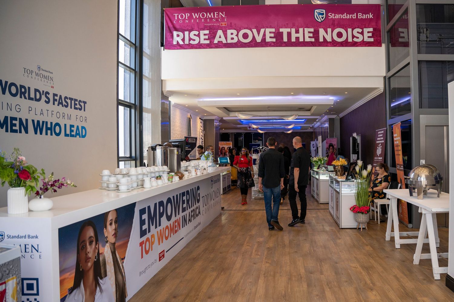 Attendees walk through a Standard Bank Top Women Conference hall with empowerment banners.