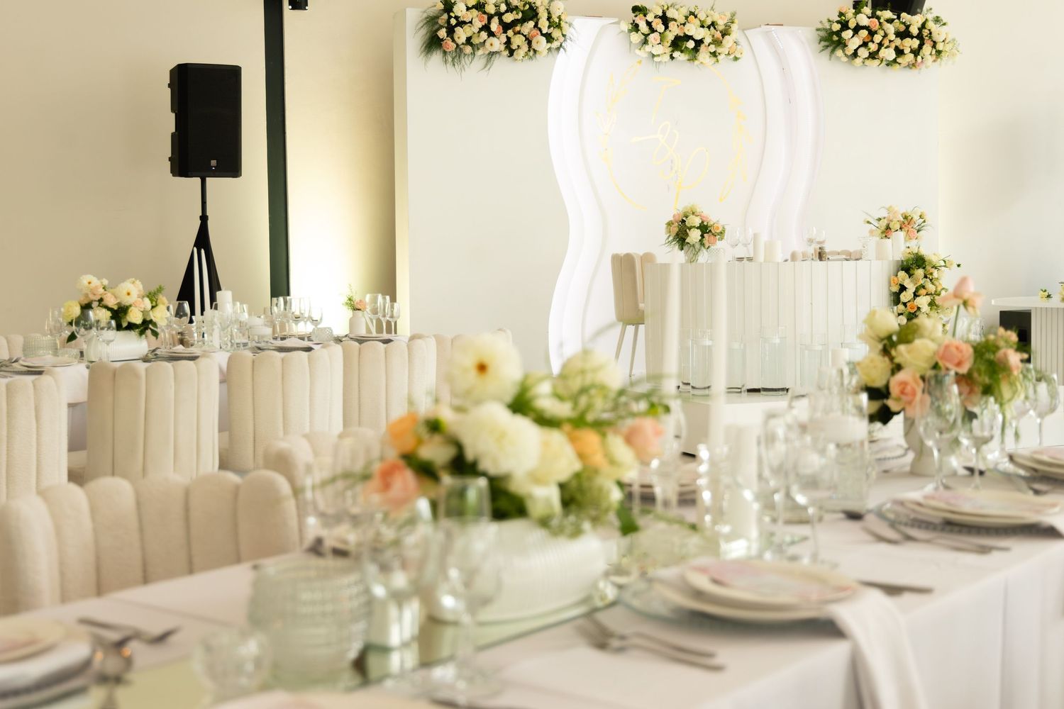 Sophisticated wedding reception table setting with white linens, crystal glassware, and soft peach floral centerpieces.