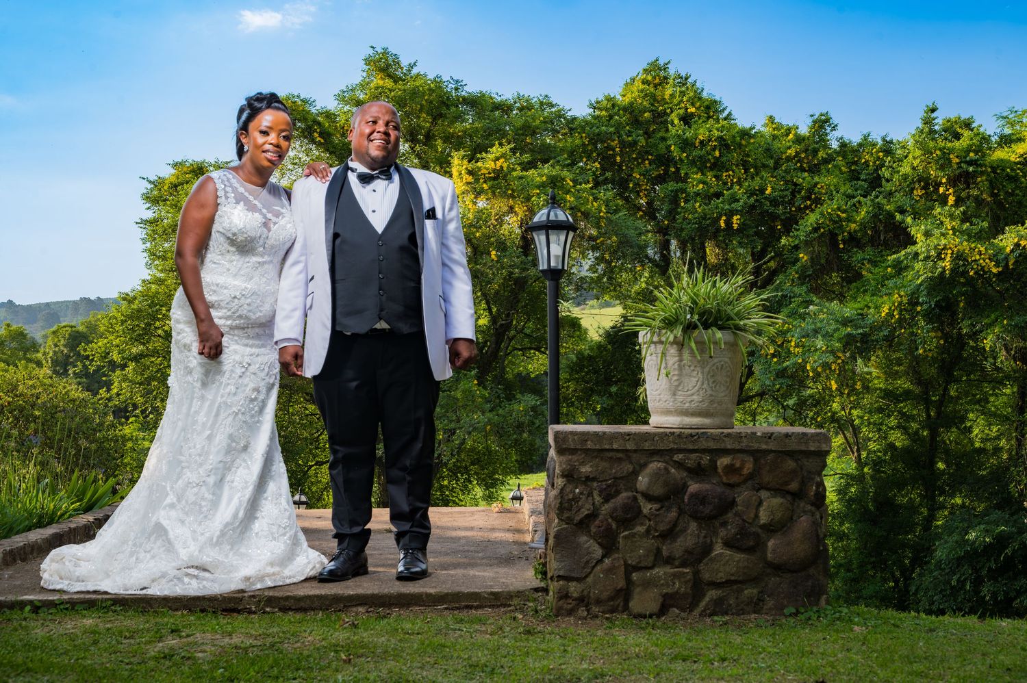Bride and groom posing together in a lush garden setting on their wedding day.