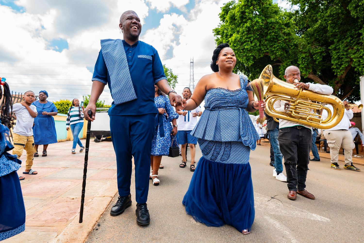 A couple in coordinating blue traditional outfits walking together during a festive cultural ceremony.