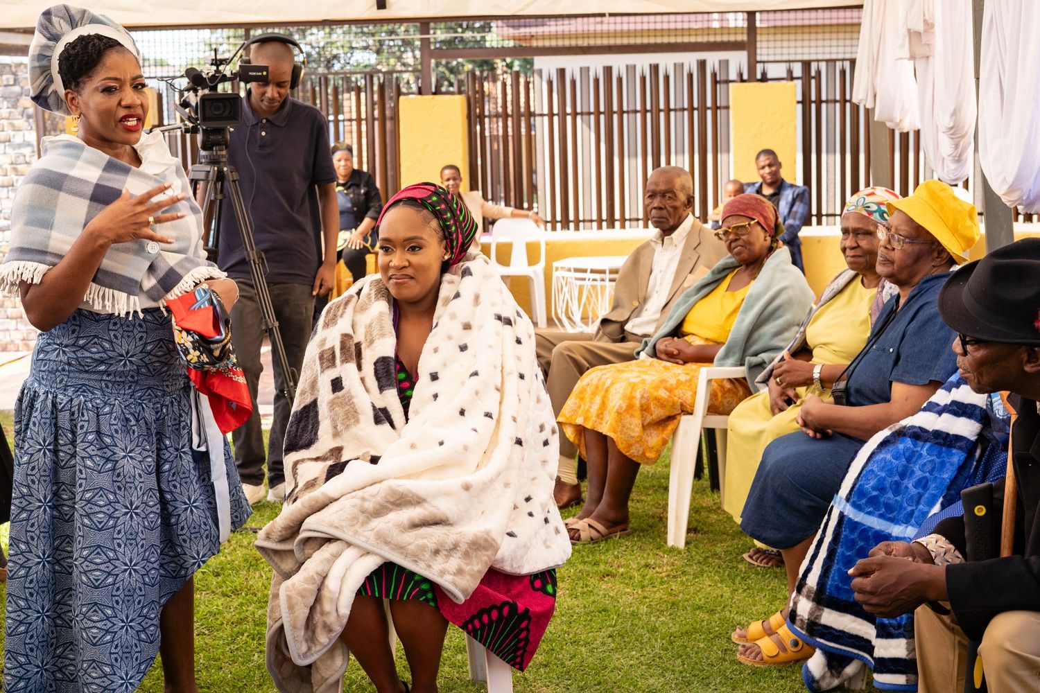Young woman wrapped in traditional blanket seated during African traditional wedding lobola ceremony.