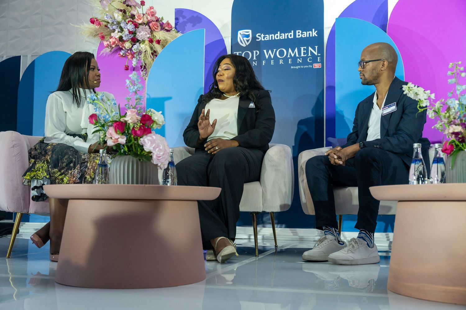 Three panelists engage in discussion at the Standard Bank Top Women Conference on stage.