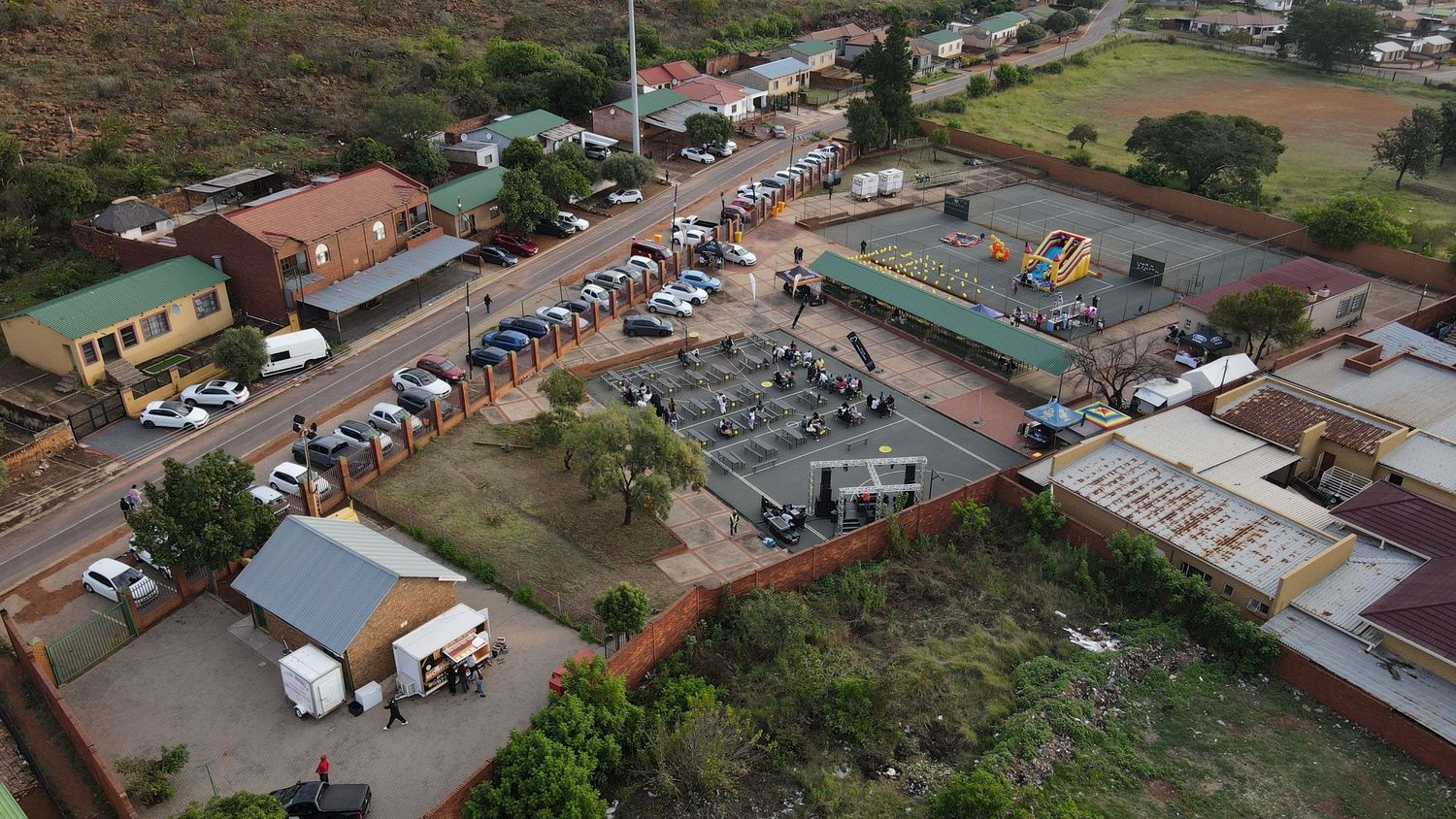 Aerial view of a small town with parked cars, buildings, and an outdoor electrical substation in a dry landscape.