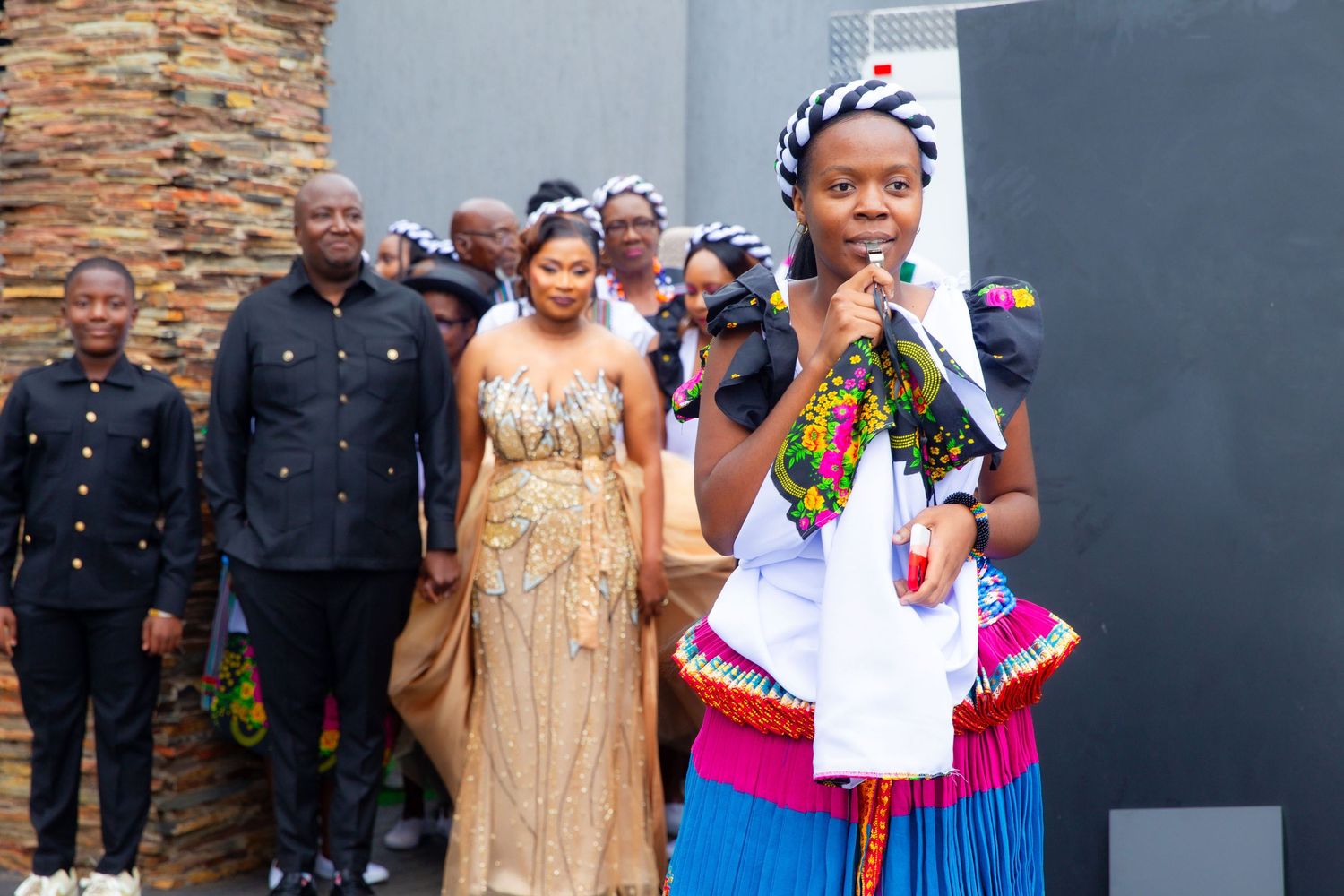 Wedding procession featuring bride in gold gown and guests in colorful traditional African dress.