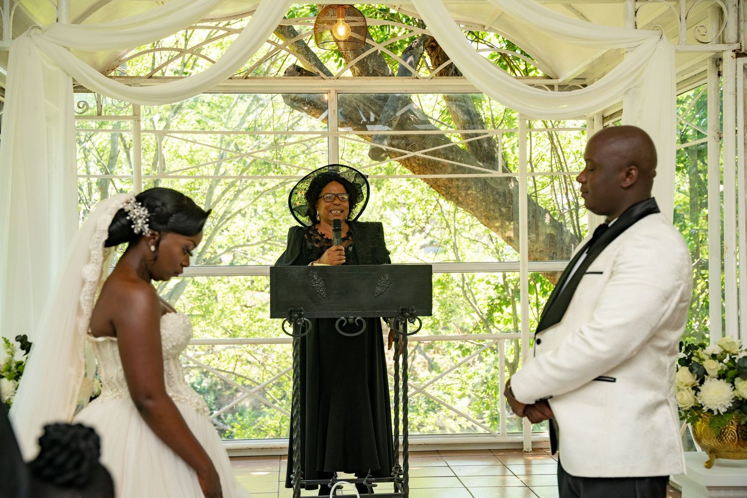Officiant presiding over a wedding ceremony in a white chapel with the couple.