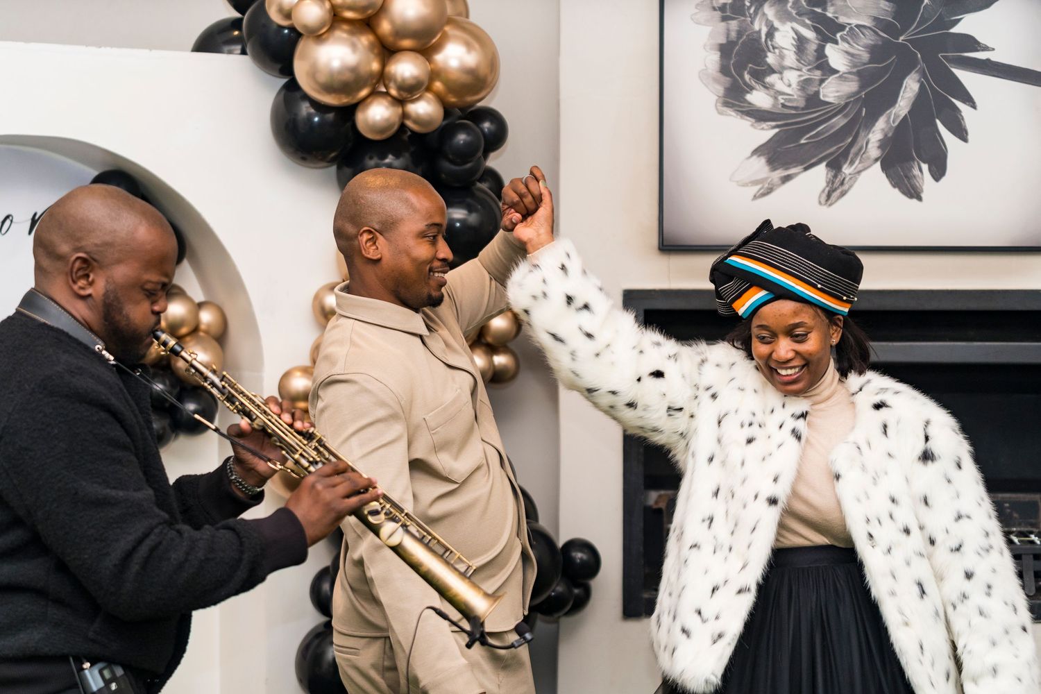 Live trumpet performance energizes guests at a stylish party with black and gold balloon arch decor.