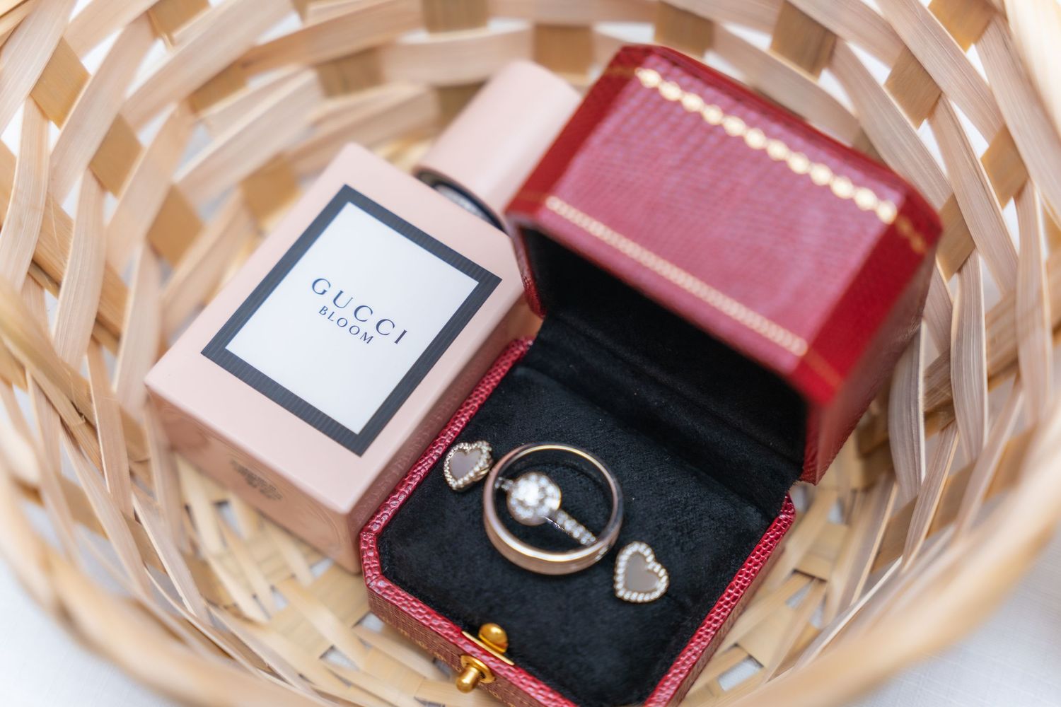 Wedding rings in red Cartier box with Gucci packaging displayed in wicker basket.