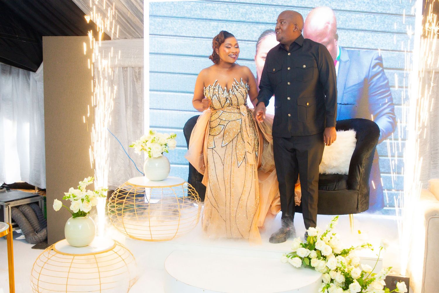 Couple in elegant attire sharing a moment at a decorated wedding reception with sparklers.