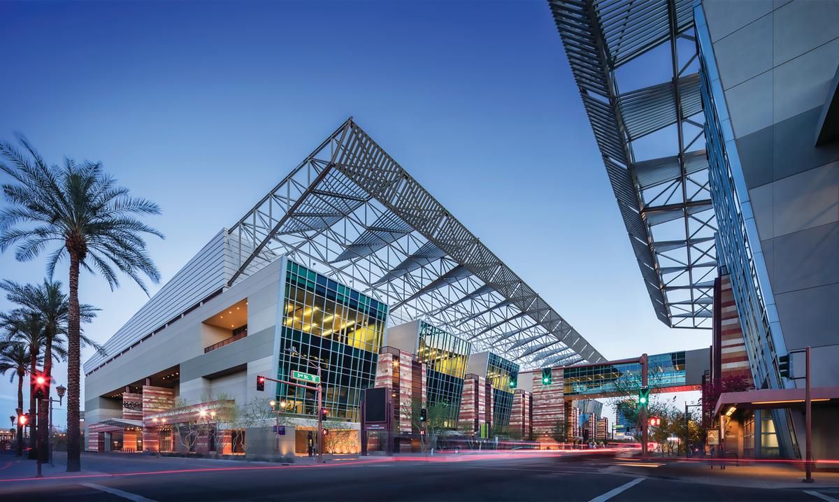 Panoramic view of a modern shopping center with glass roof architecture and palm trees at dusk.