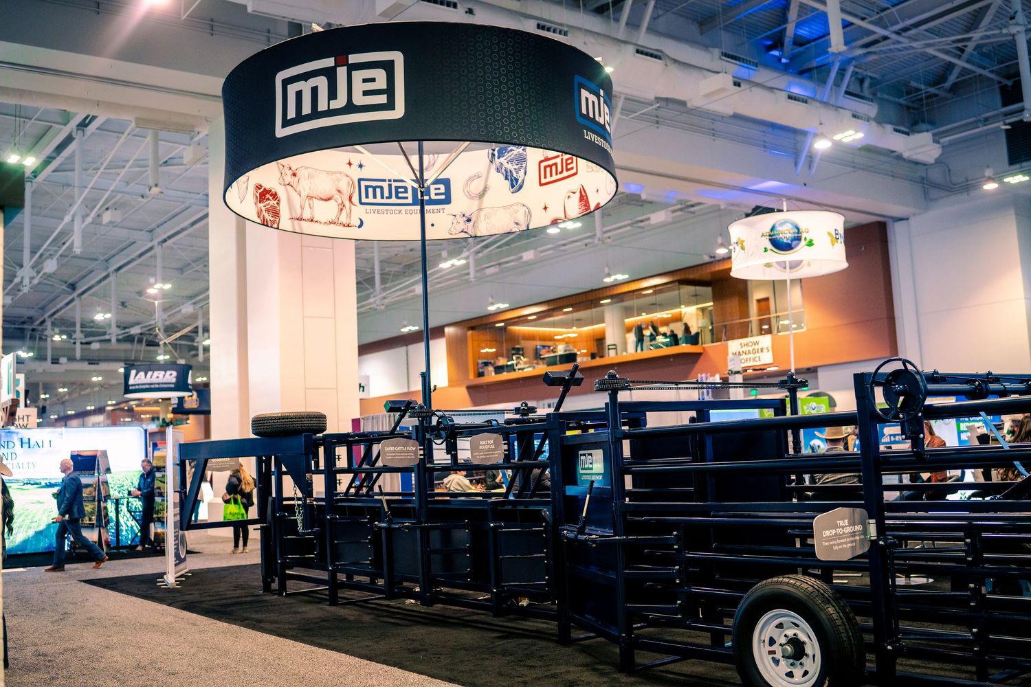 Trade show booth display with illuminated circular signage and black utility vehicles on display at an indoor exhibition.