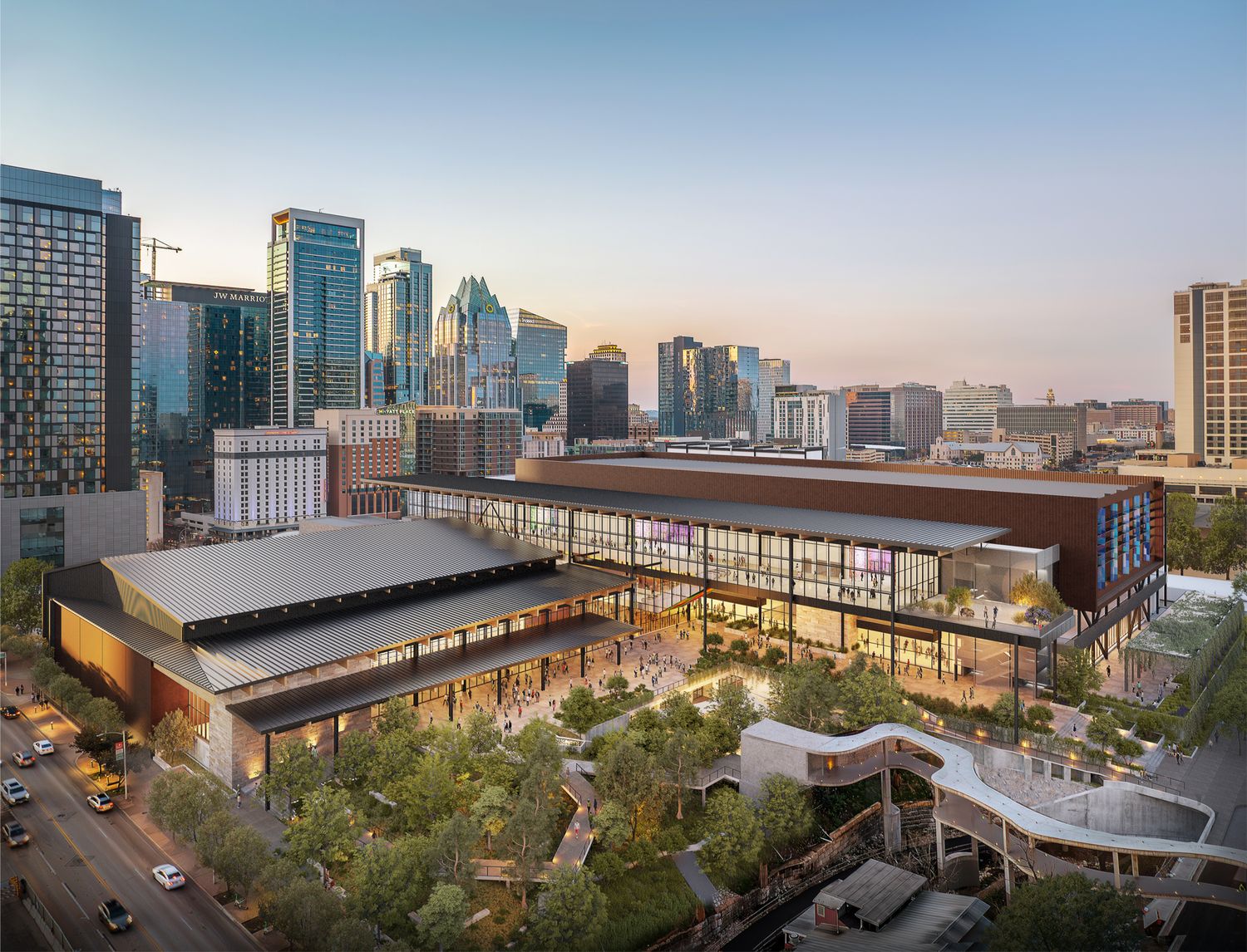 Modern convention center with glass facade and landscaped plaza in downtown Minneapolis at sunset with city skyline backdrop.