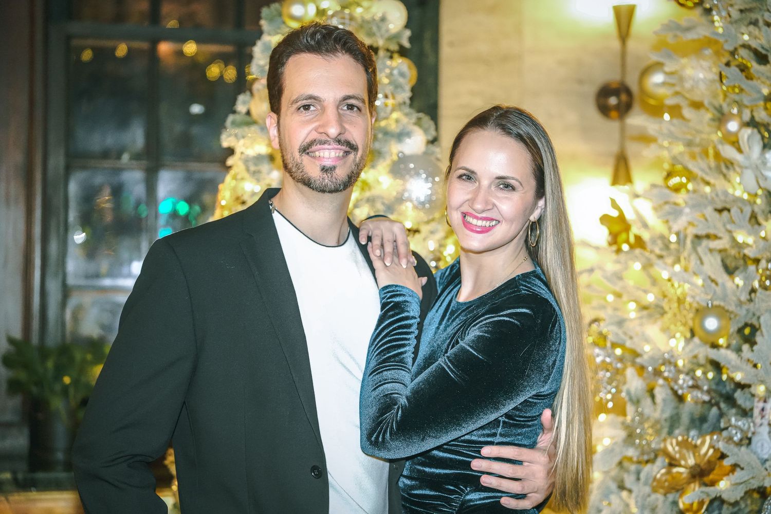 Couples posing for photos at an evening event with decorative gold lights in background.