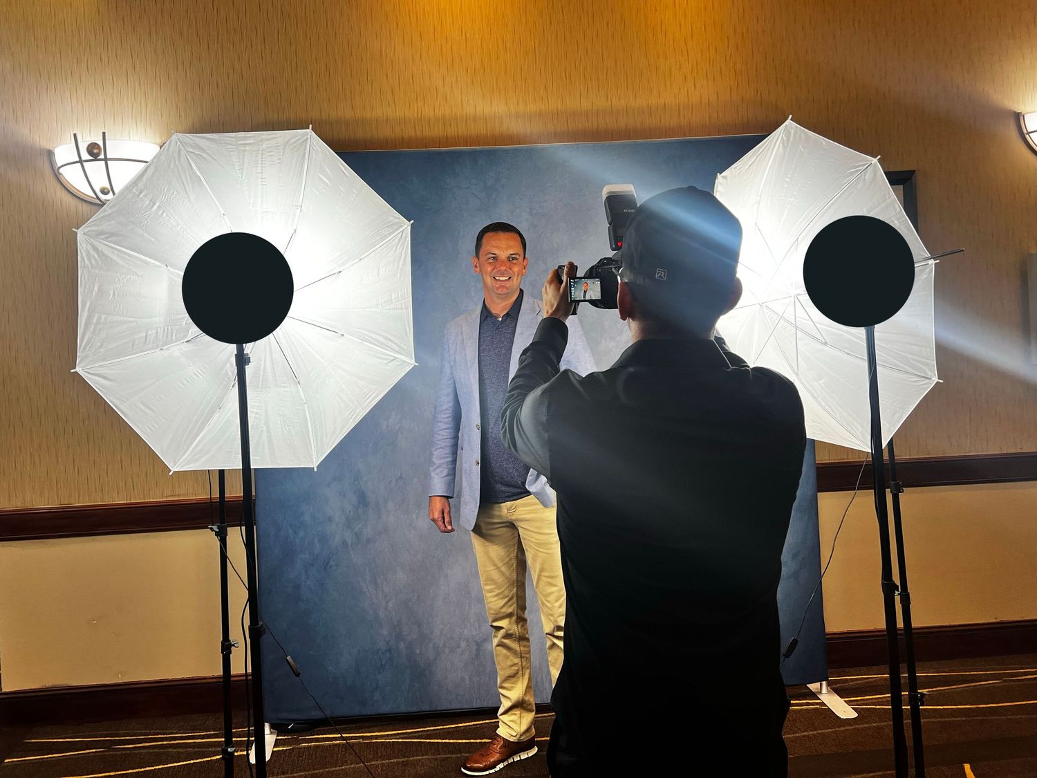 Professional photo studio setup with white umbrellas, softboxes and lighting equipment arranged in a room.