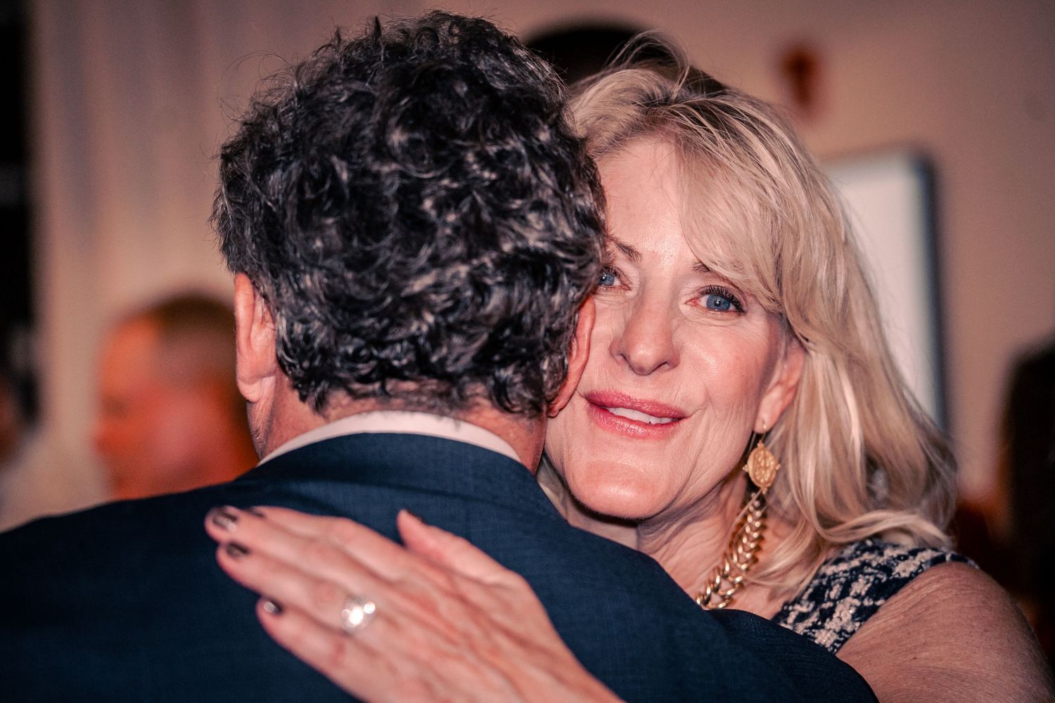 People embracing during an emotional moment at an evening party.