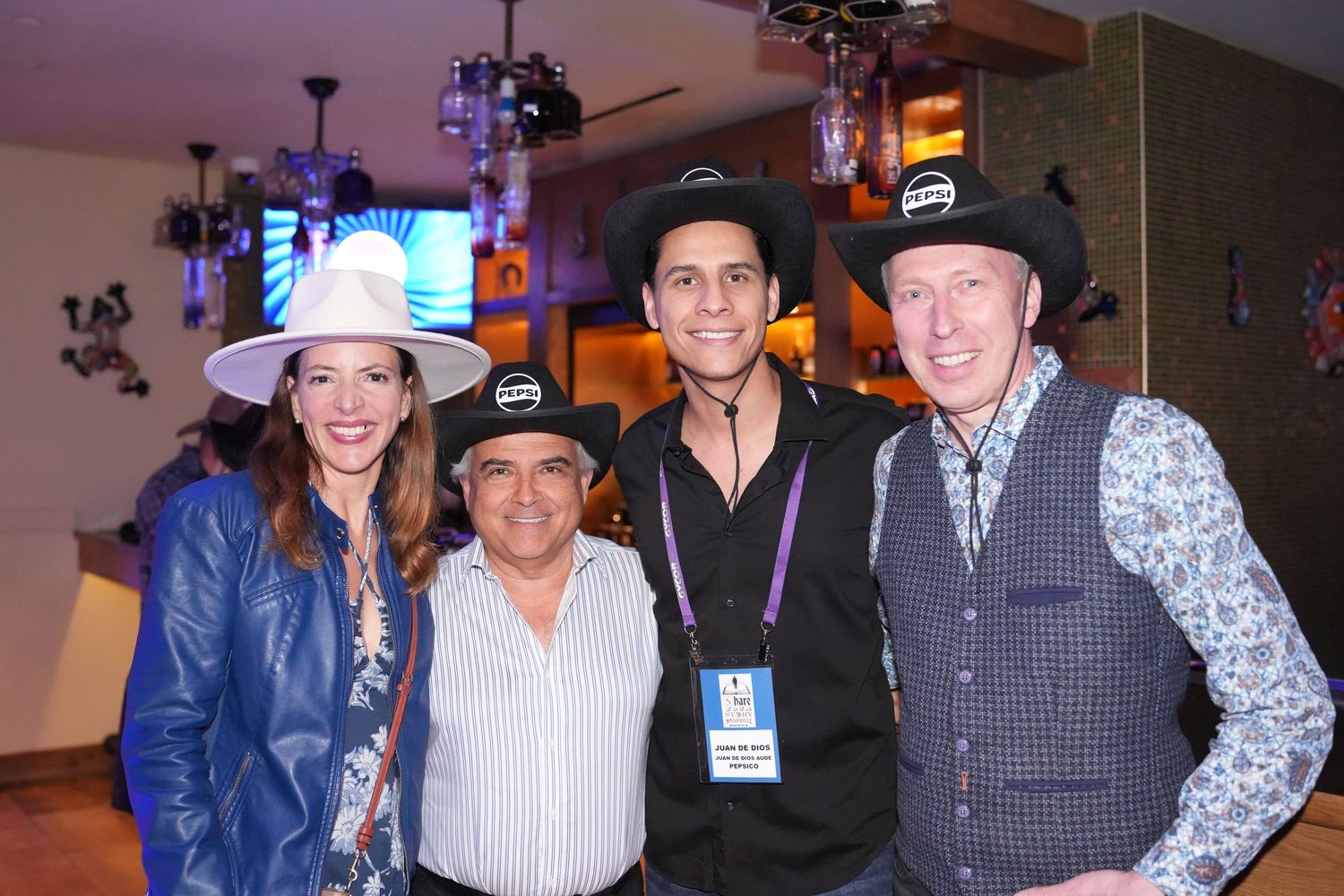 Event attendees gathered together for photos in western attire and cowboy hats.