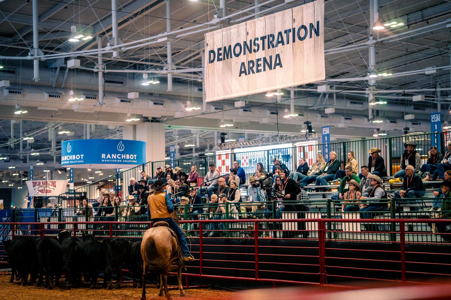 A large indoor demonstration arena with seating and fencing setup for an event at a convention center.