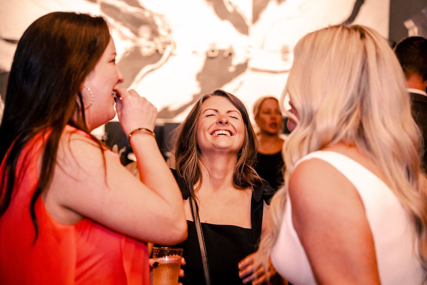 People dancing and celebrating at a party with warm lighting and festive atmosphere.