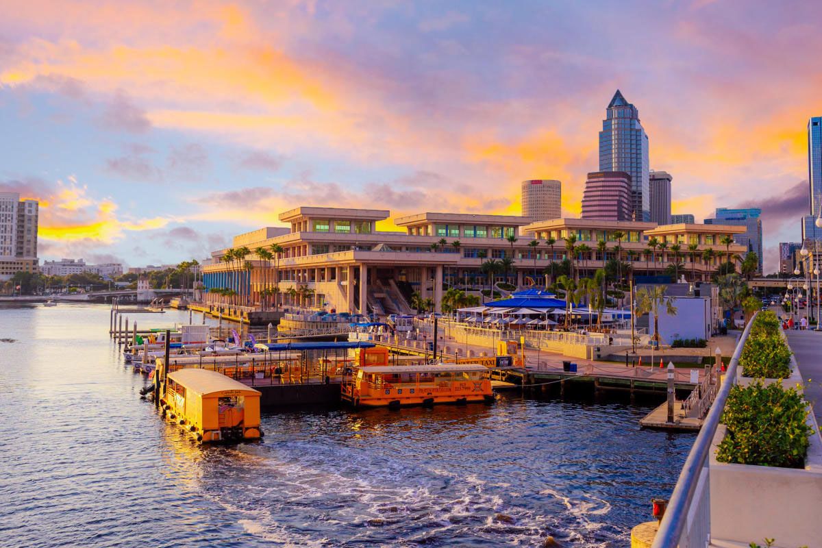 Colorful sunset over Port Tampa Bay marina with boats docked and downtown skyline in the background.