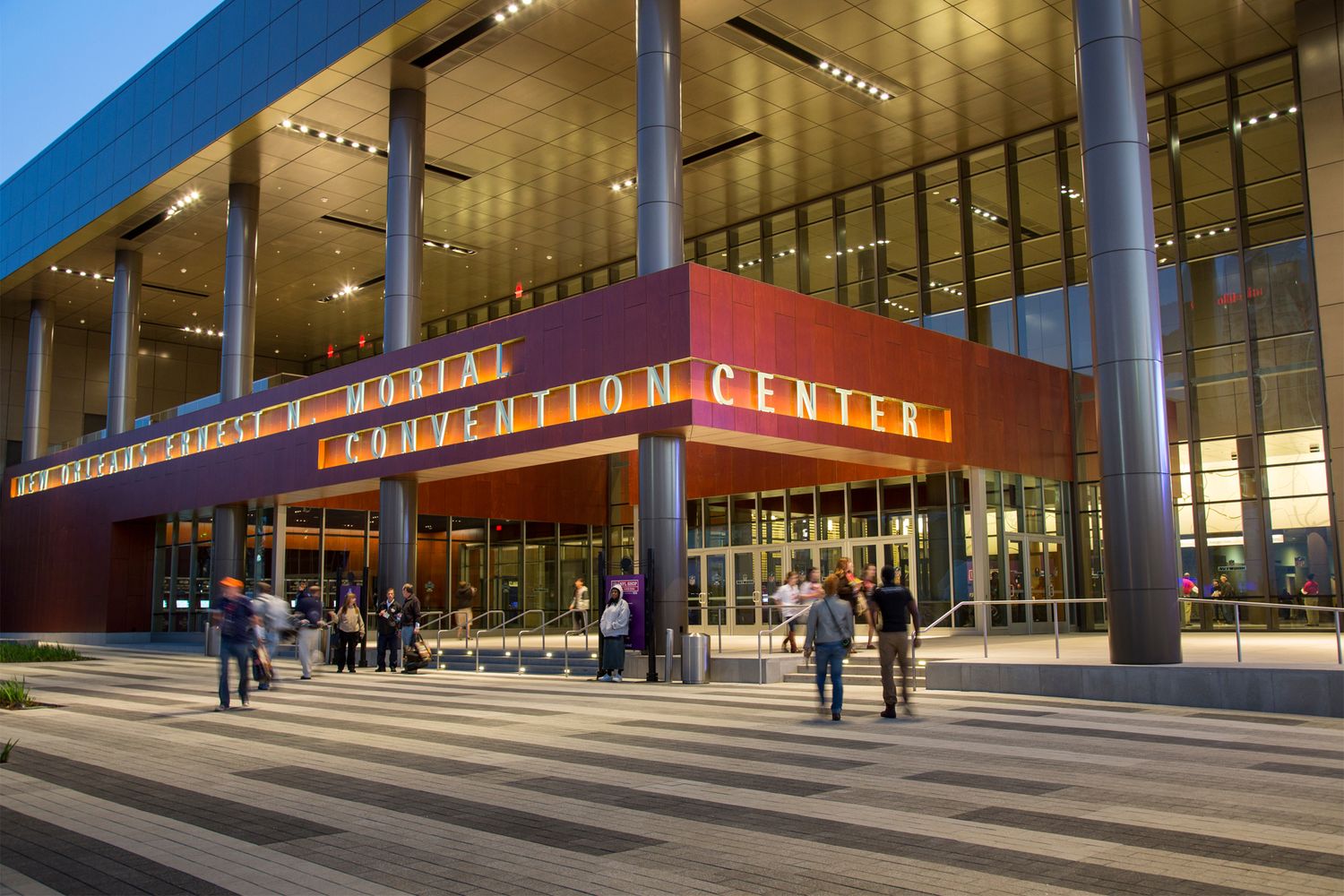 Modern glass and steel entrance to the Wharton Center for Performing Arts with illuminated signage at dusk.