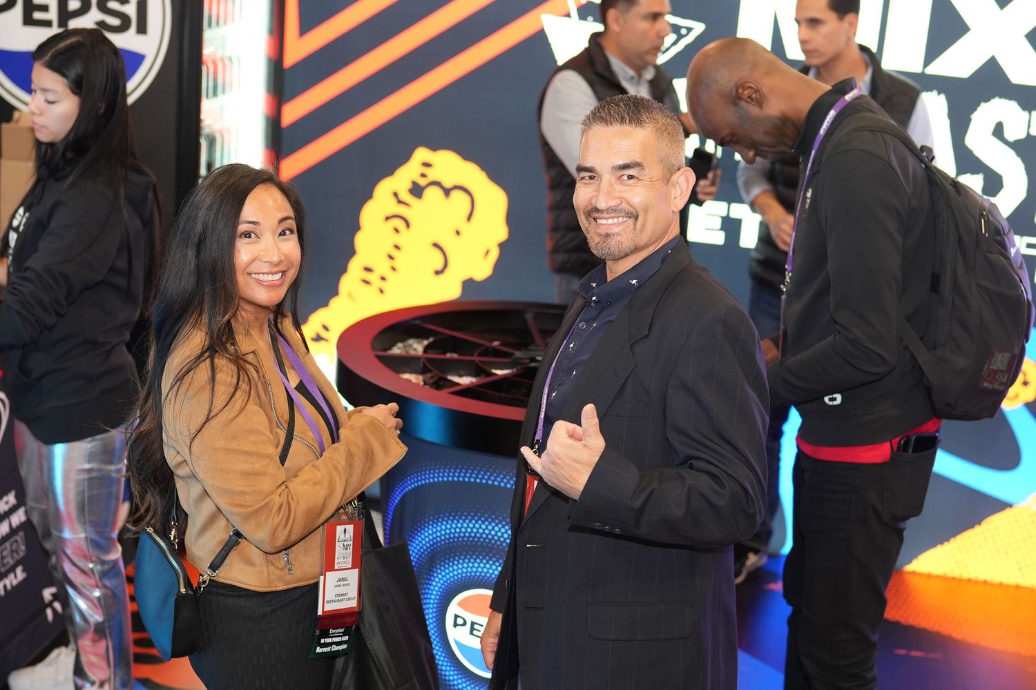 People posing at an event with branded displays and signage in the background.