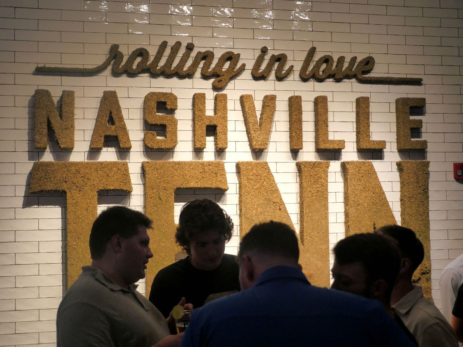 Silhouettes of people gathered under Nashville sign with gold lettering.