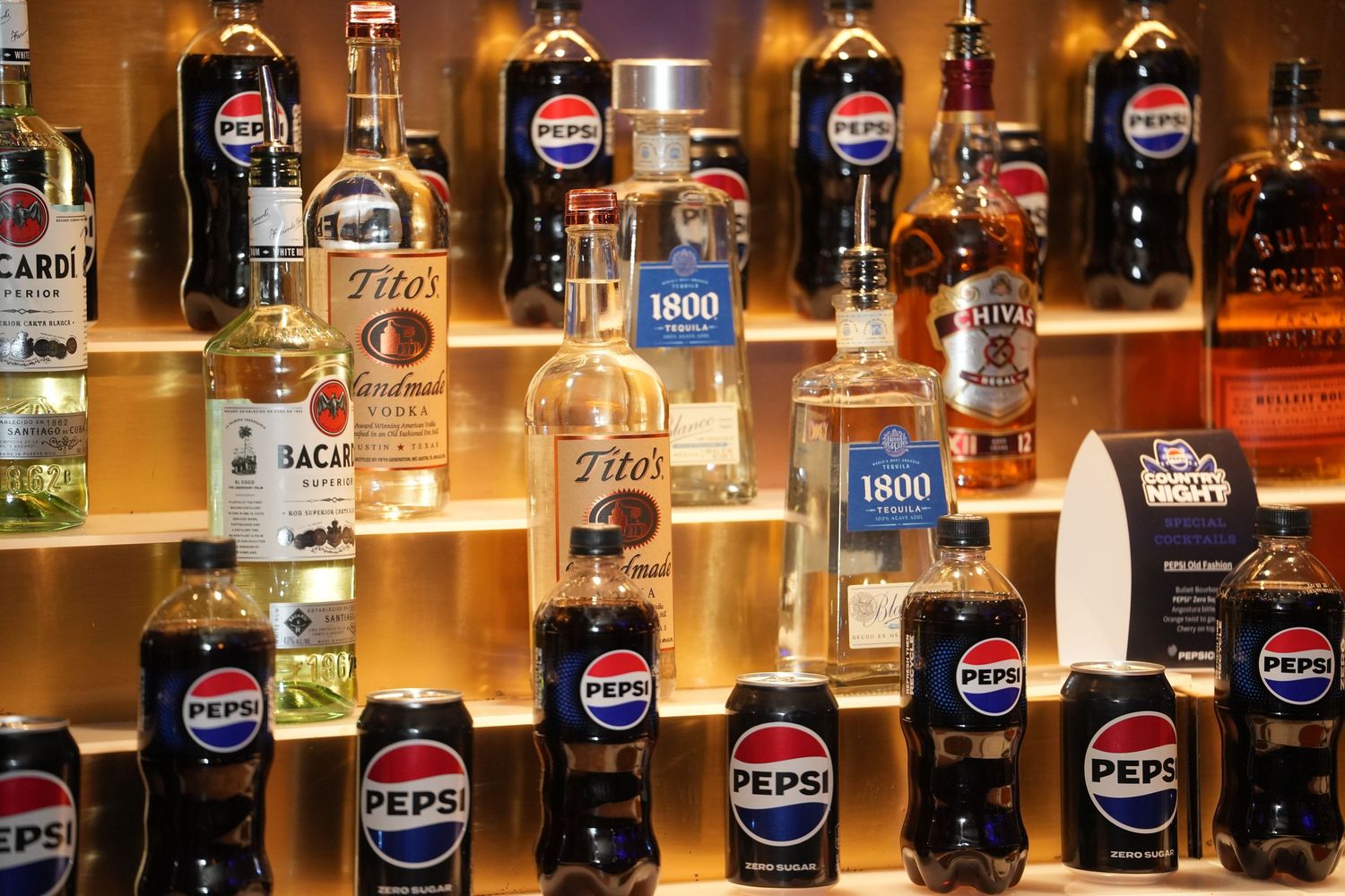 Bar shelf display featuring vintage Pepsi bottles and various beverage bottles illuminated with warm lighting.
