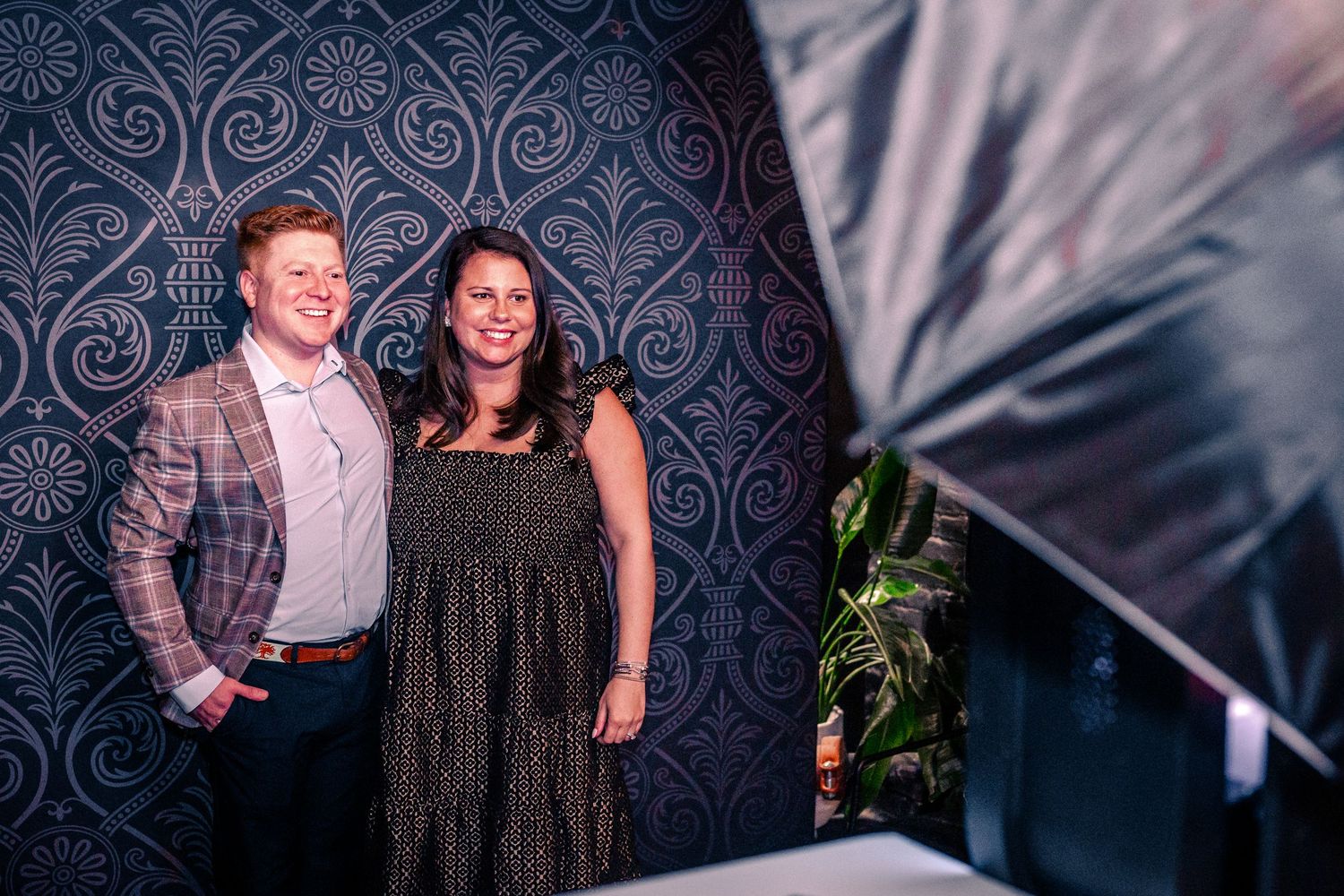 People gathered against a dark patterned wall at an elegant evening social function.