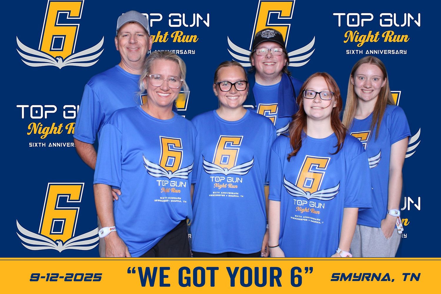Row of blue and gold Top Gun themed banners with text and logos displayed at an event.