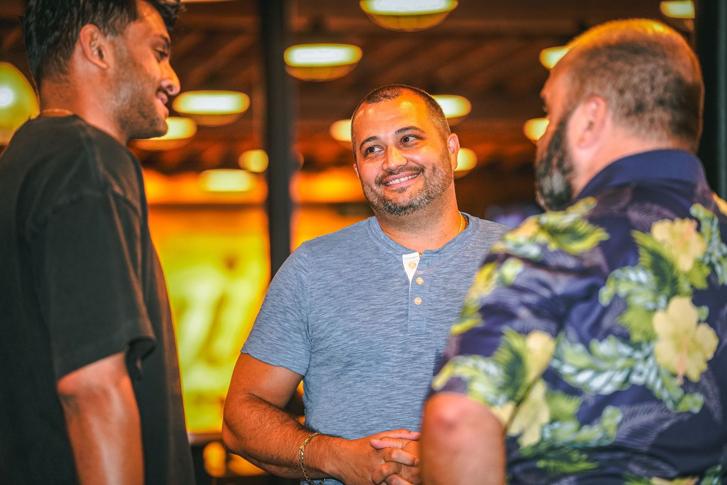 People mingling and laughing at a casual indoor party with warm lighting.