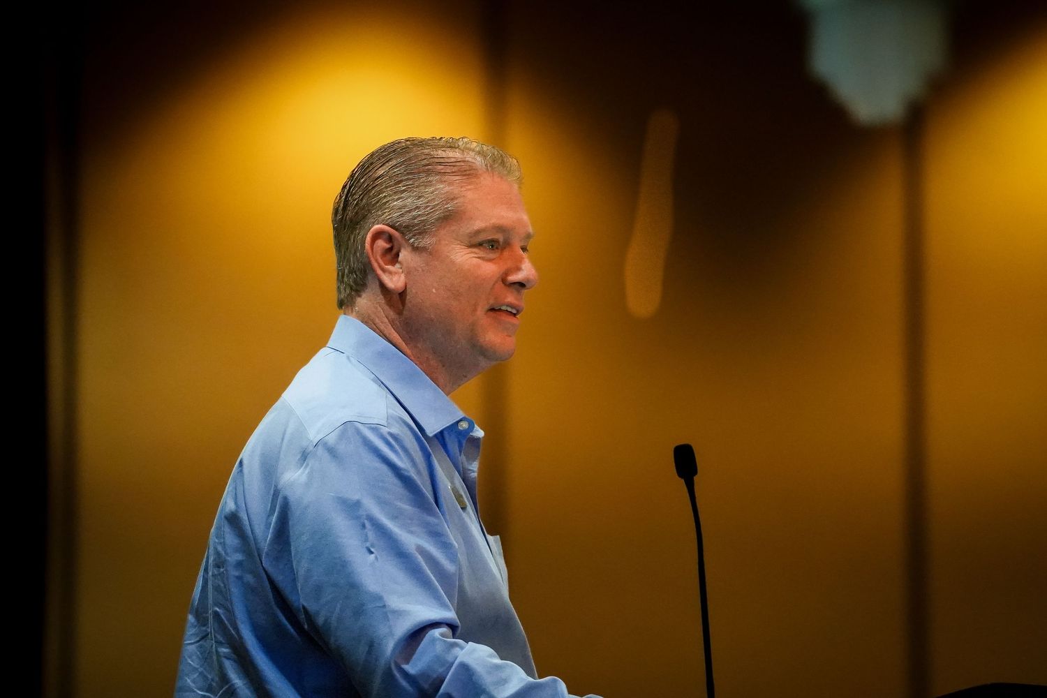Speaker presenting at a podium during an indoor conference or meeting.