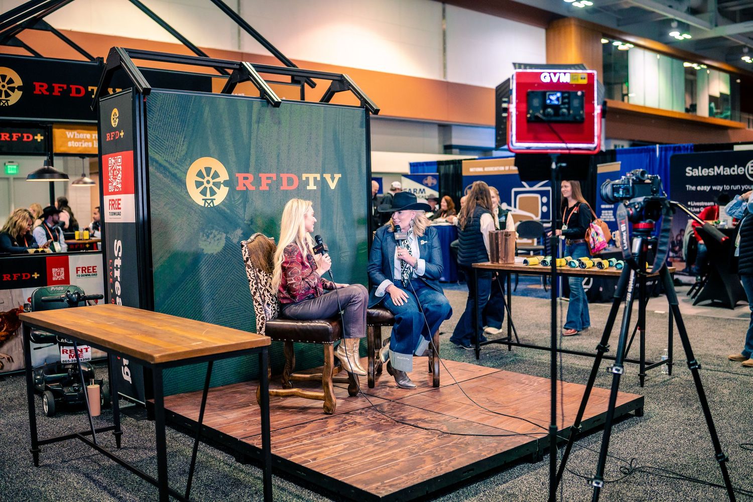 A professional television studio setup with cameras, monitors, and lighting equipment arranged on a wooden floor.