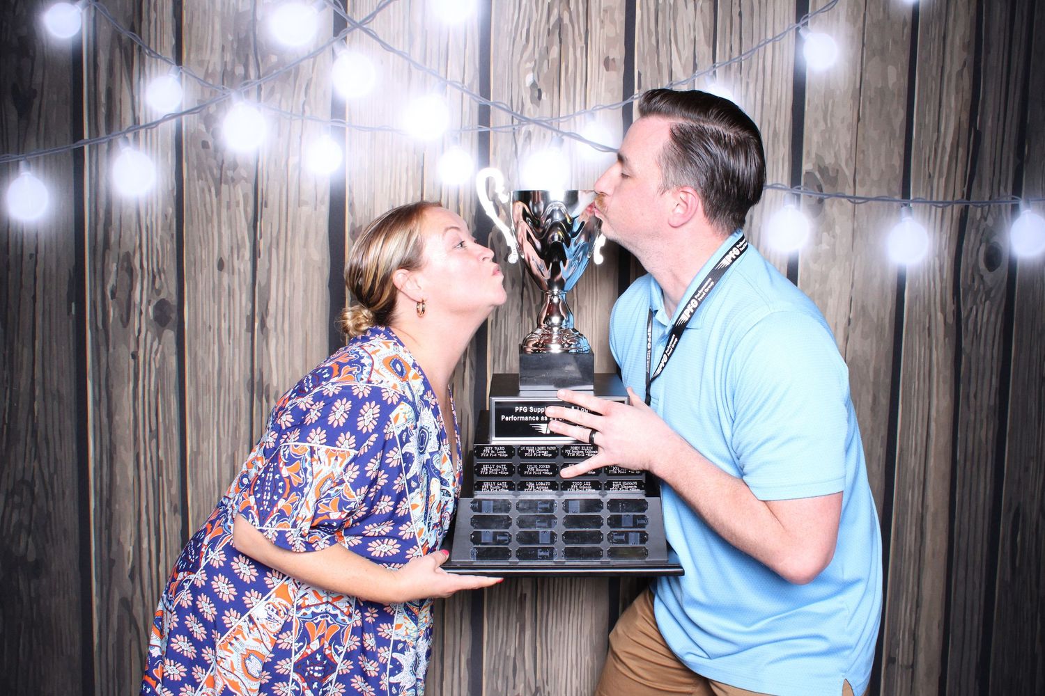 Photo booth strip showing couples posing together with festive lighting and wooden backdrop at a convention.