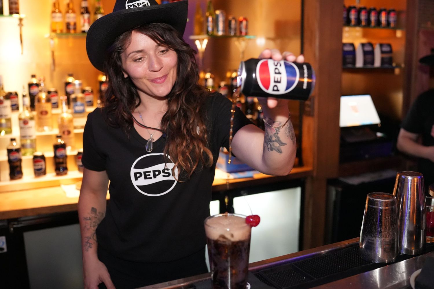 Bar counter with Pepsi branding and bottles displayed against warm backlit shelving.