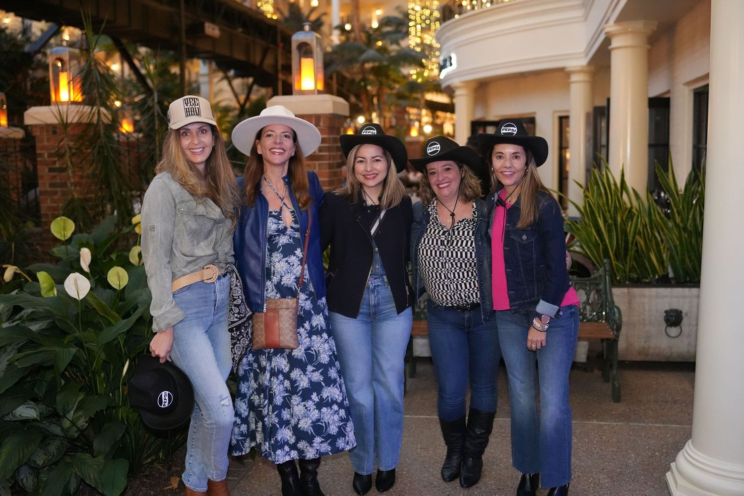 Group photo at an outdoor event with decorative lights and white columns in the background.
