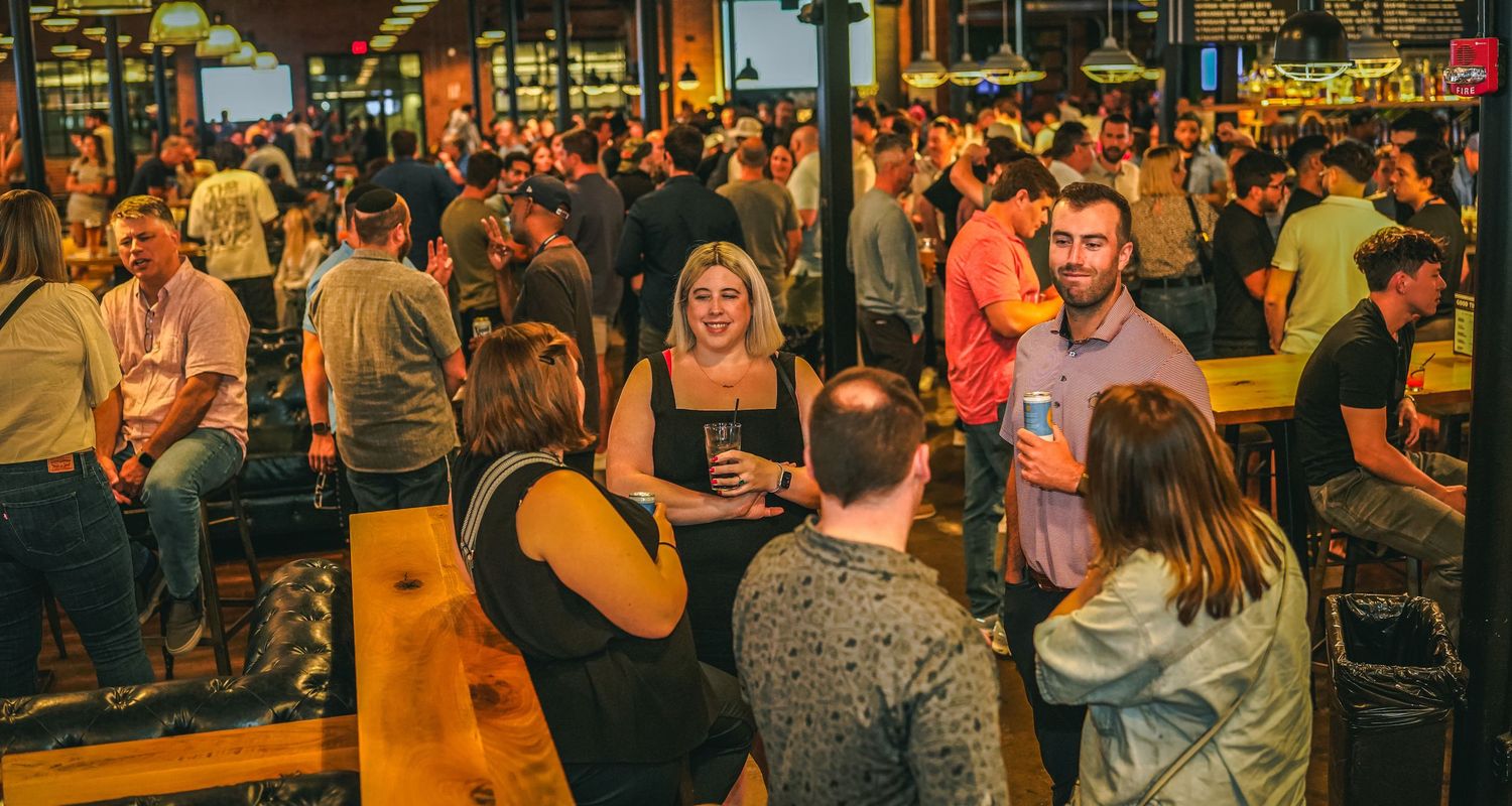 Large group of people networking and socializing at an indoor business or conference event.