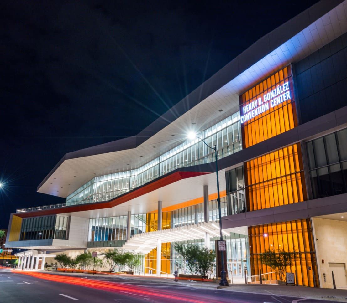 Modern architectural building illuminated at night with orange and white lighting creating a dramatic geometric facade.