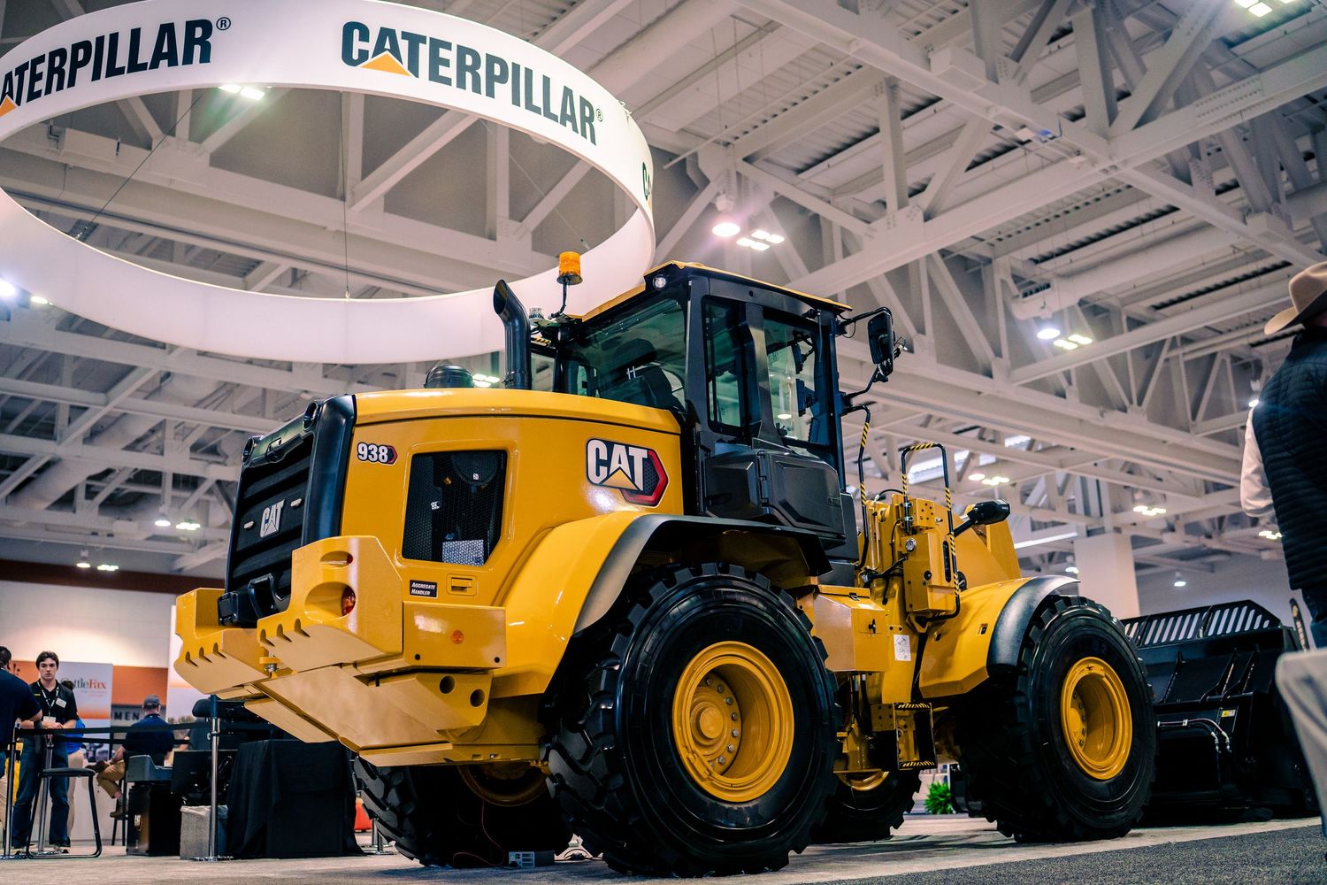 A lineup of yellow Caterpillar construction vehicles including dump trucks and rollers on display in a bright showroom.