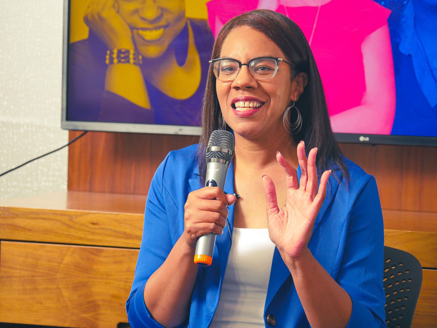 Professional speaker delivering an energetic presentation in front of colorful backdrop.