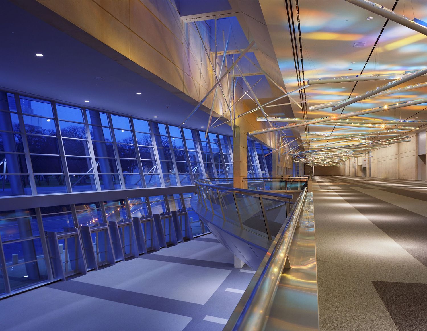 Modern airport terminal walkway with curved glass windows and illuminated ceiling panels creating a futuristic atmosphere.